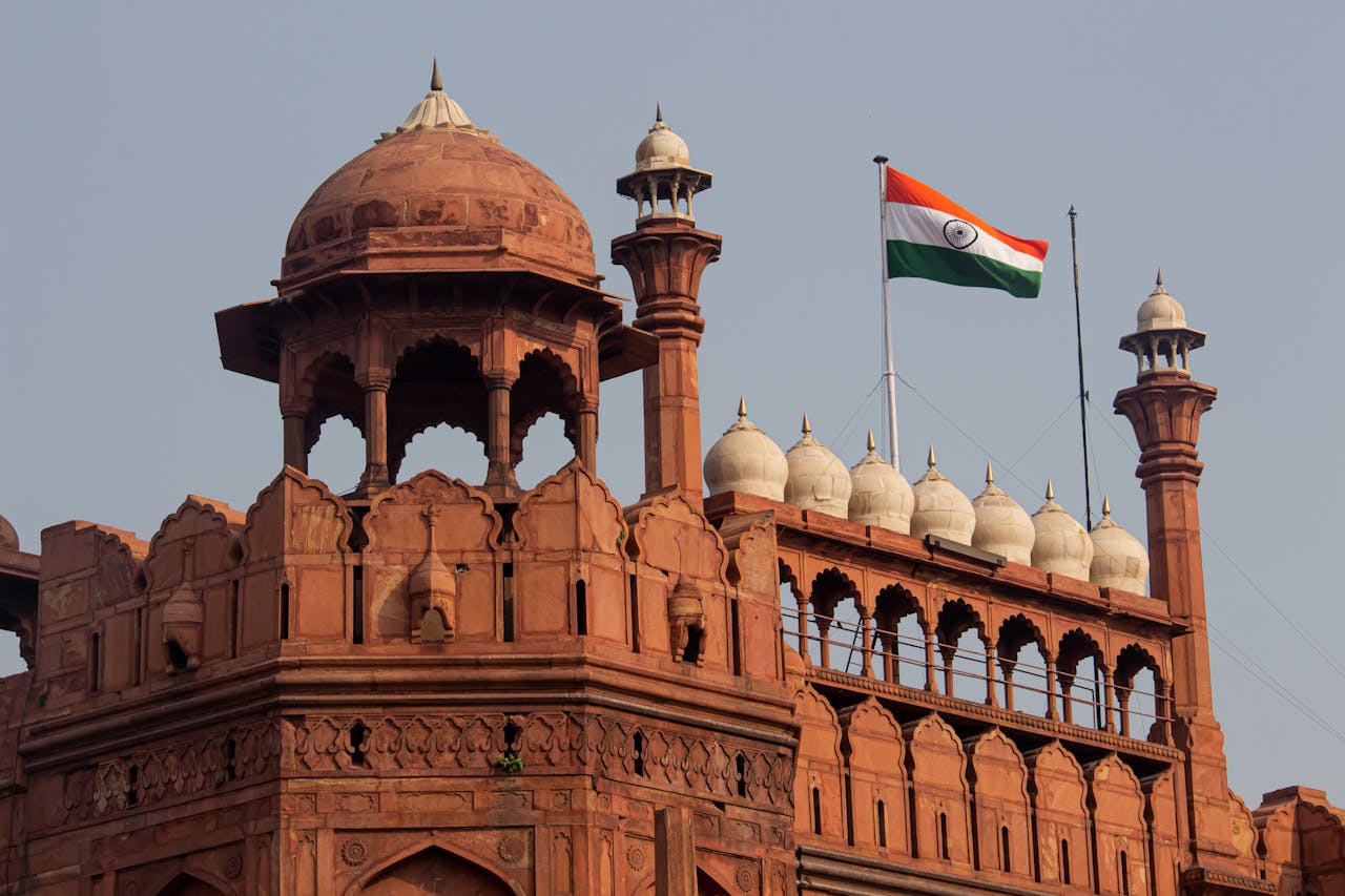 Historic red sandstone building with domes and Indian flag, likely part of a legal or governmental structure.