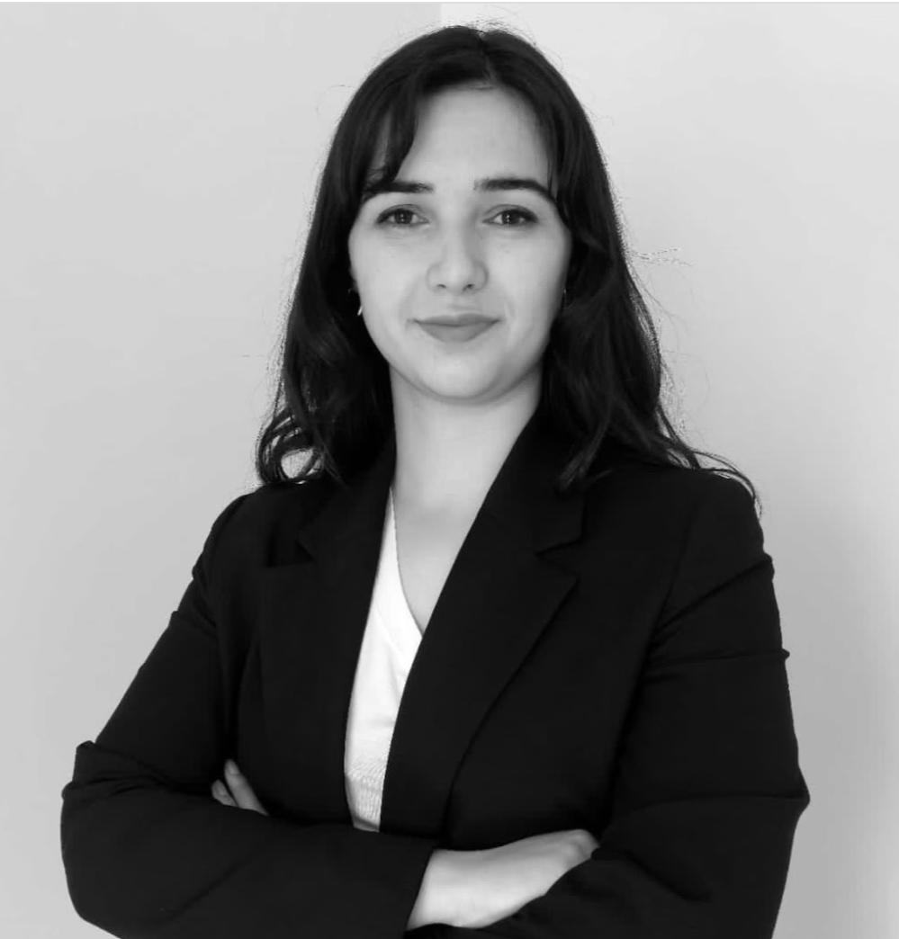 Lawyer standing with arms crossed, presenting a confident demeanor against a neutral background.