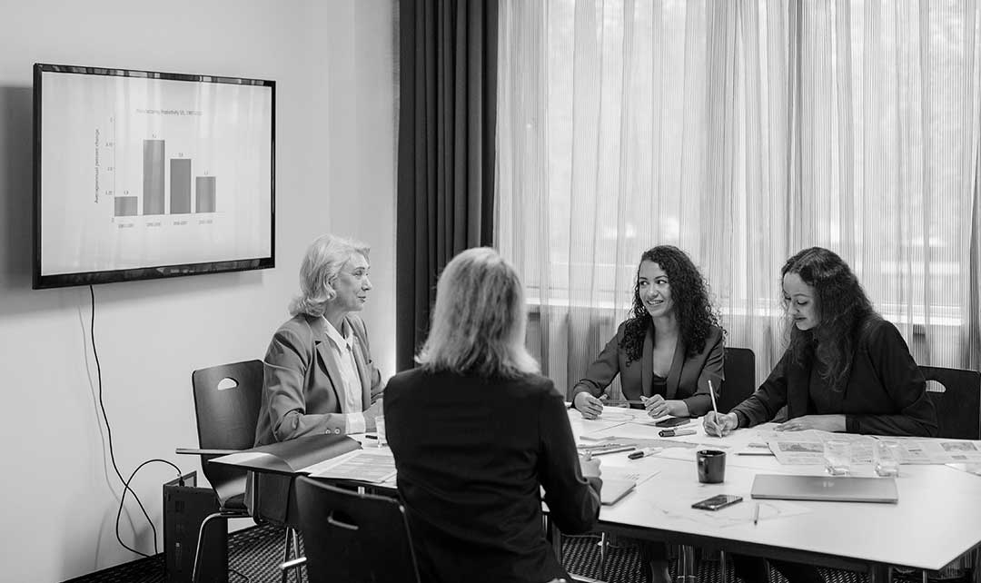 Lawyers collaborating in a conference room, reviewing documents with a presentation on a screen.