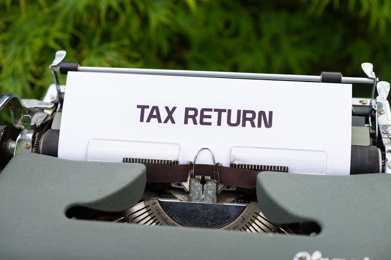 Typewriter displaying a page with the words "TAX RETURN" on it, set against a green background.