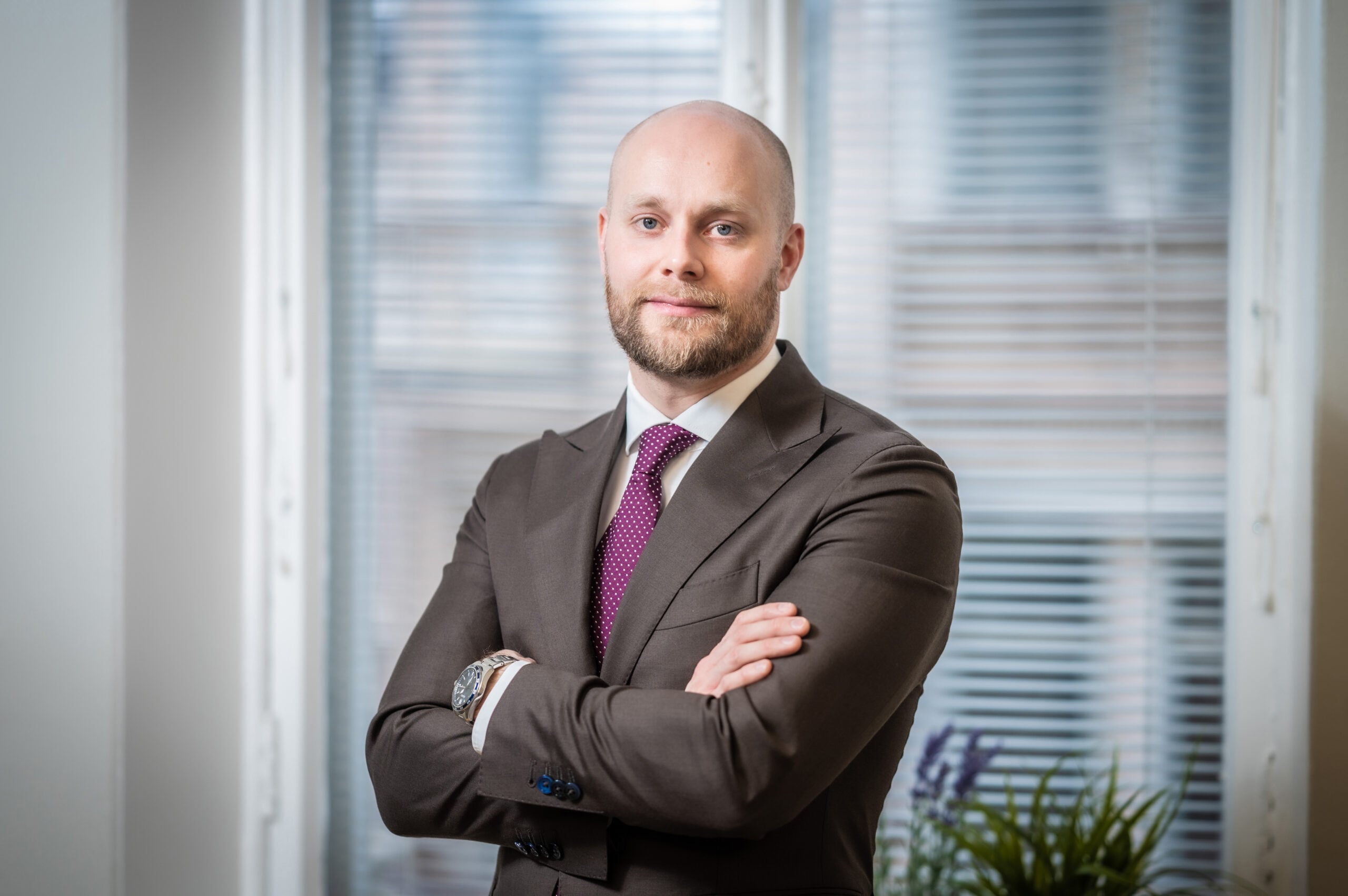 Lawyer standing confidently with arms crossed in a well-lit office setting.