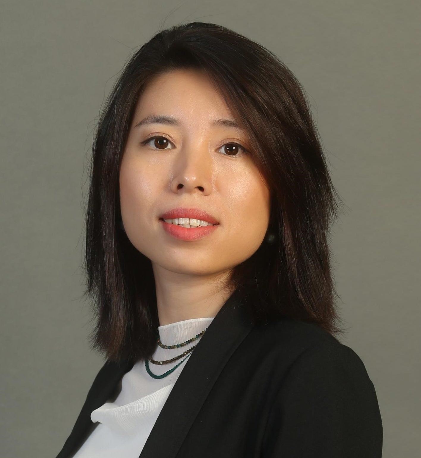 Legal professional portrait of a woman in a blazer, smiling confidently against a neutral background.