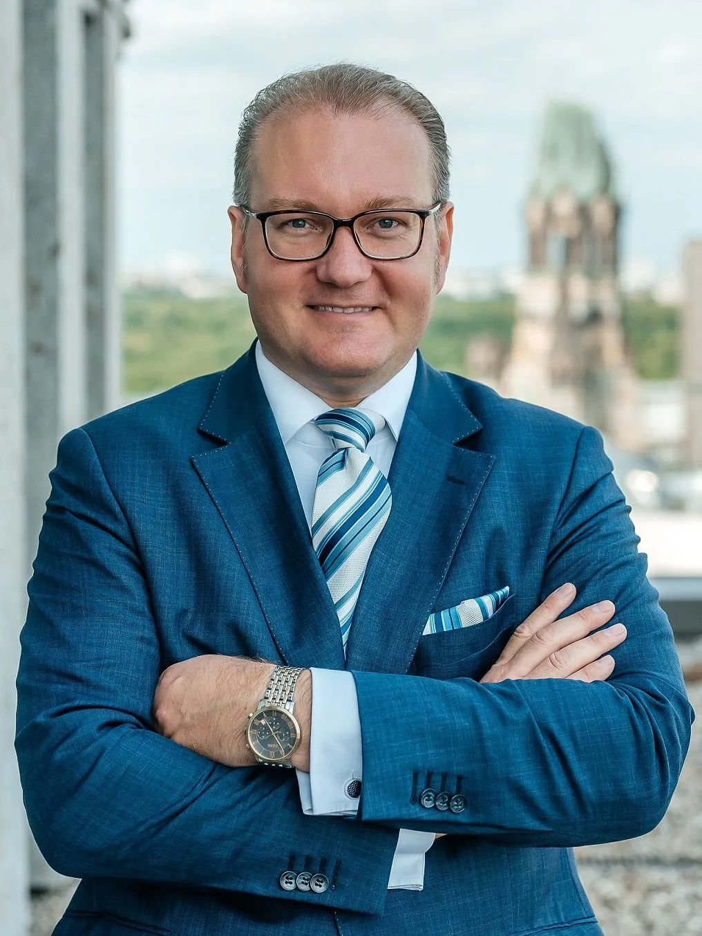 Lawyer in a blue suit, arms crossed, standing in a modern office with cityscape backdrop.