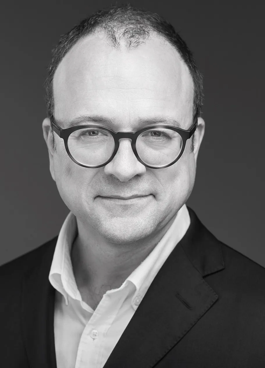 Legal professional with glasses, wearing a suit, smiling against a neutral background.