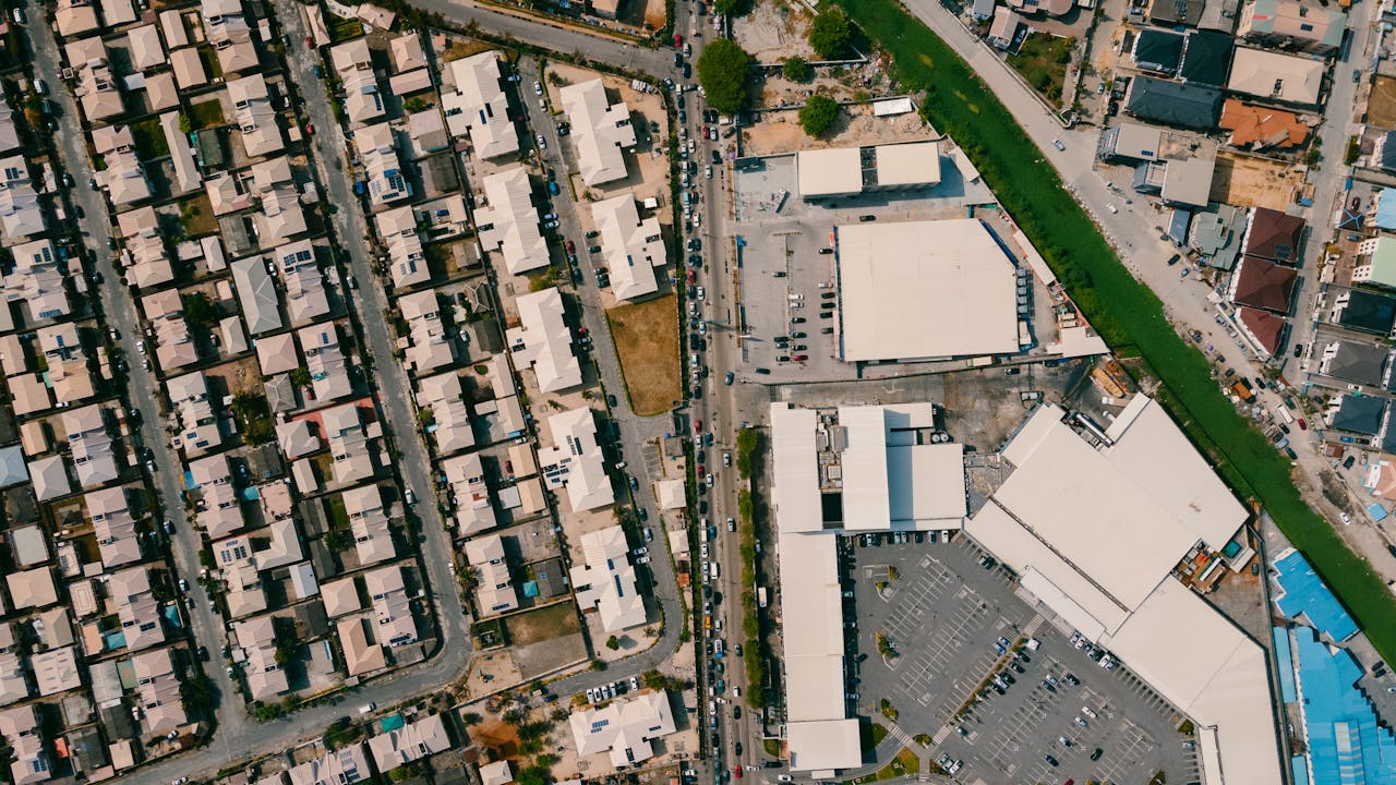 Aerial view of residential area with houses, streets, and adjacent commercial parking lot.