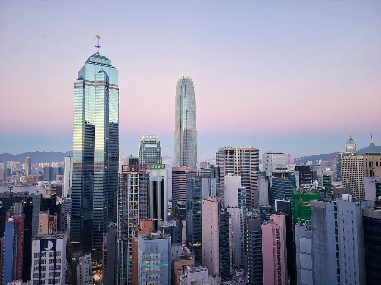 City skyline featuring modern skyscrapers at dusk with a pastel sky in the background.