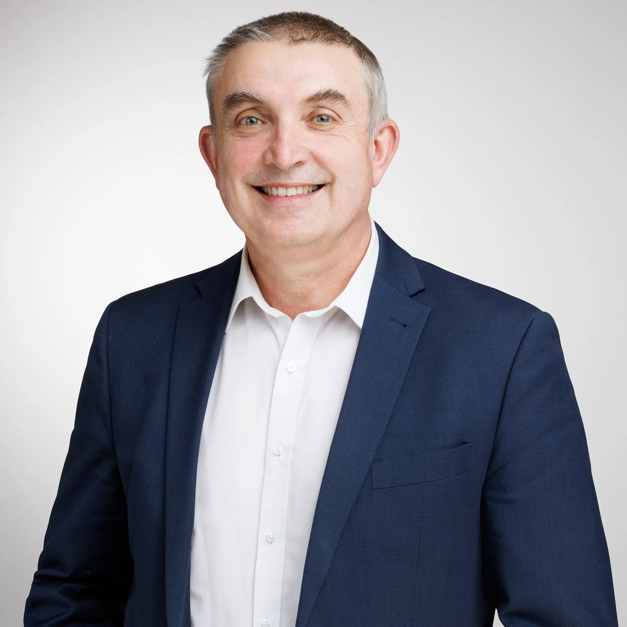 Smiling attorney wearing a suit against a neutral background, representing a professional legal demeanor.