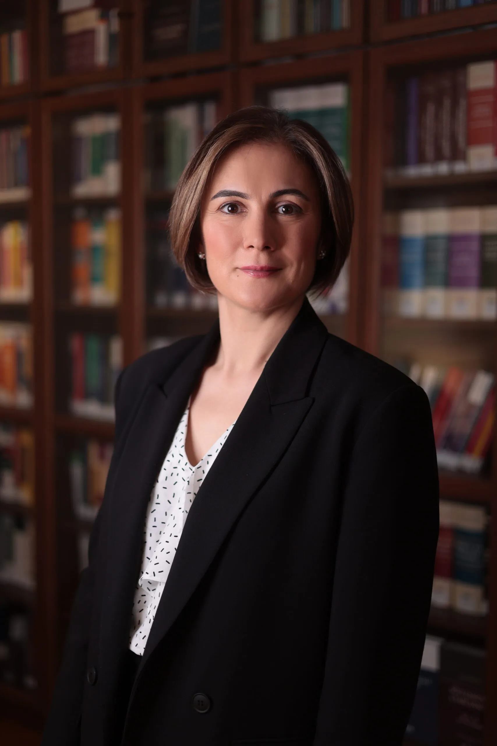 Lawyer posed in front of bookshelves filled with legal texts in an office setting.