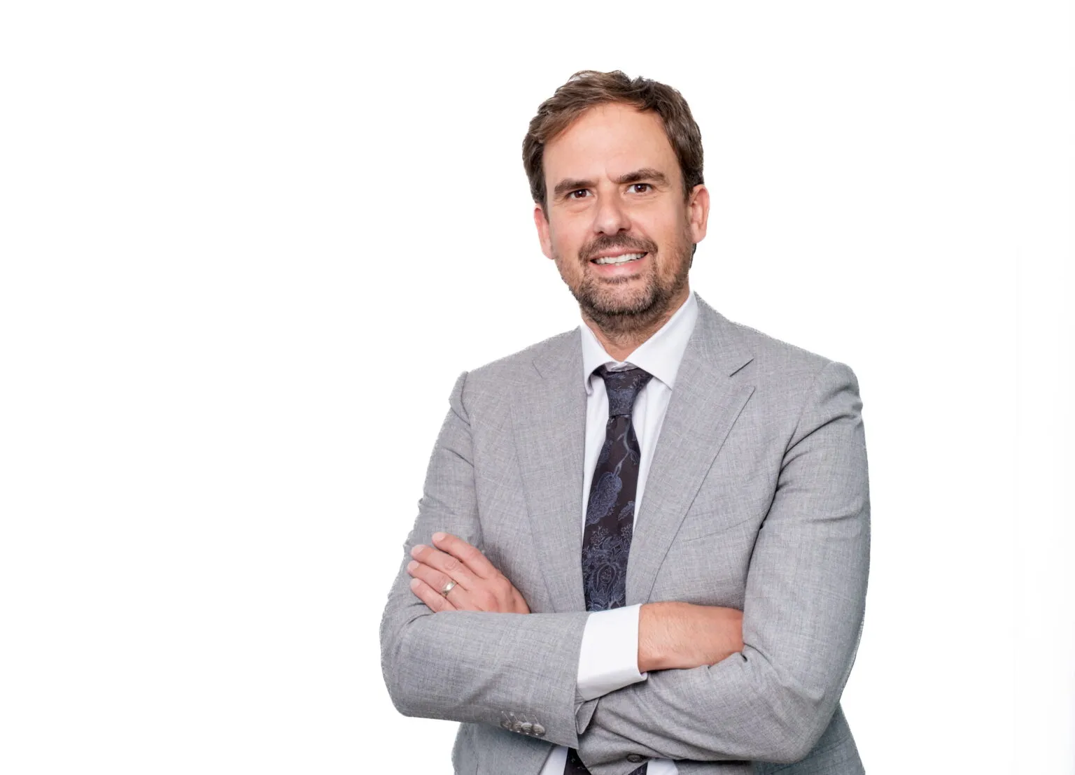 Lawyer in a gray suit, smiling with arms crossed, posing against a plain white background.