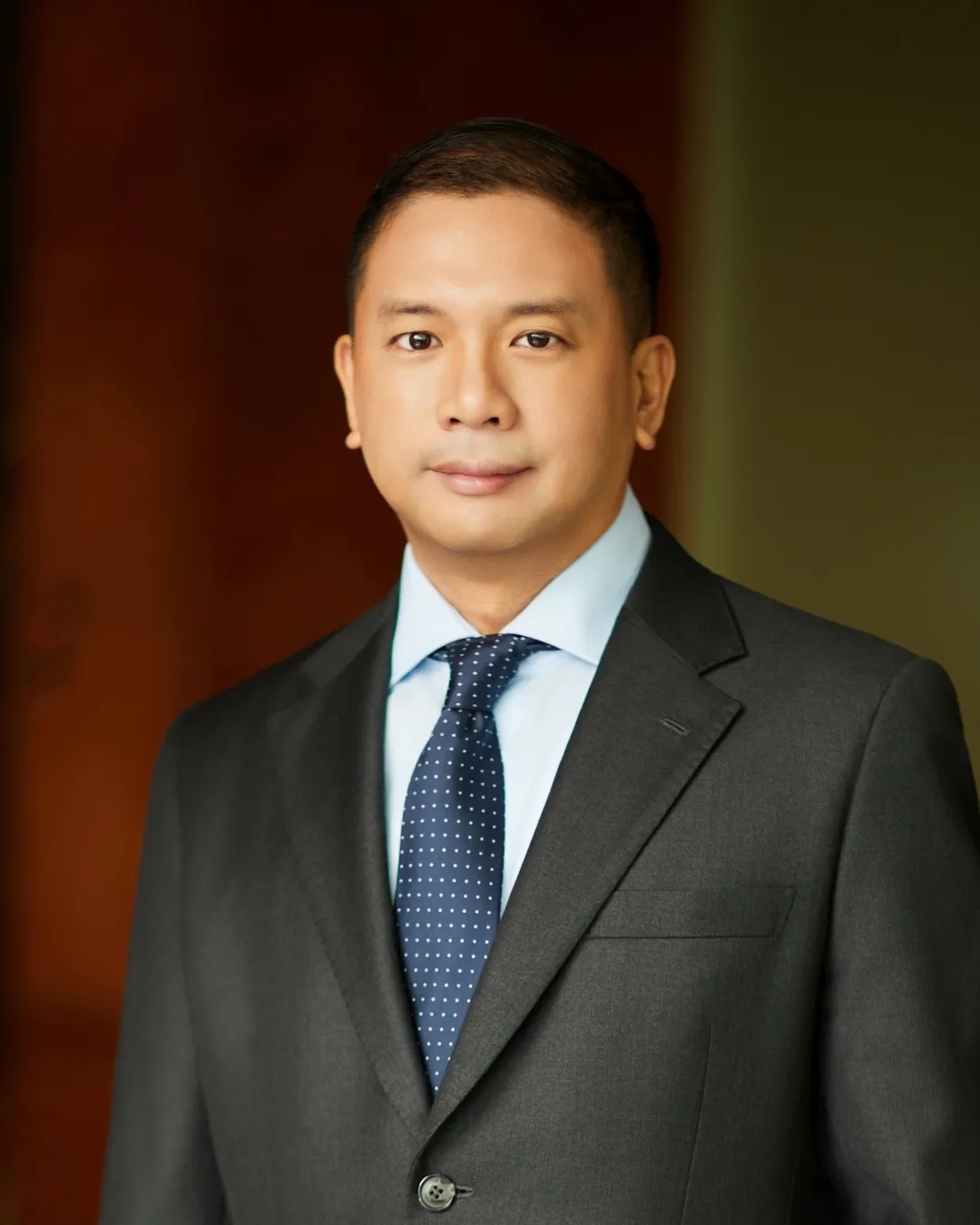 Attorney in gray suit and polka dot tie, posing confidently against a neutral background.