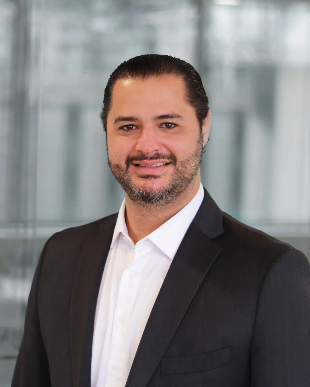 Lawyer in a suit smiling against a modern office background.