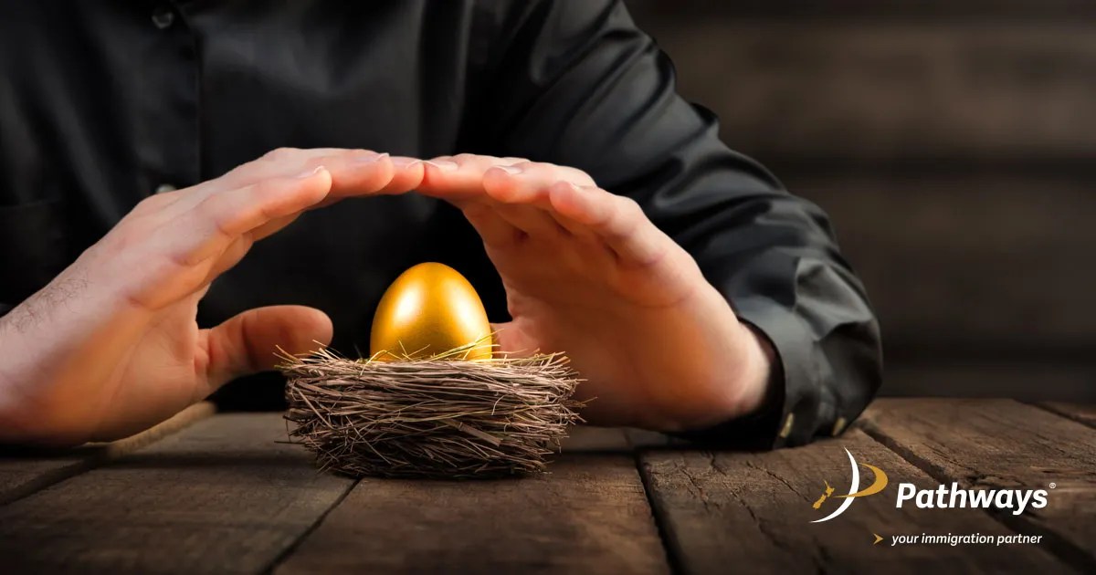Hands protecting a golden egg resting in a nest on a wooden surface, symbolizing value and security.