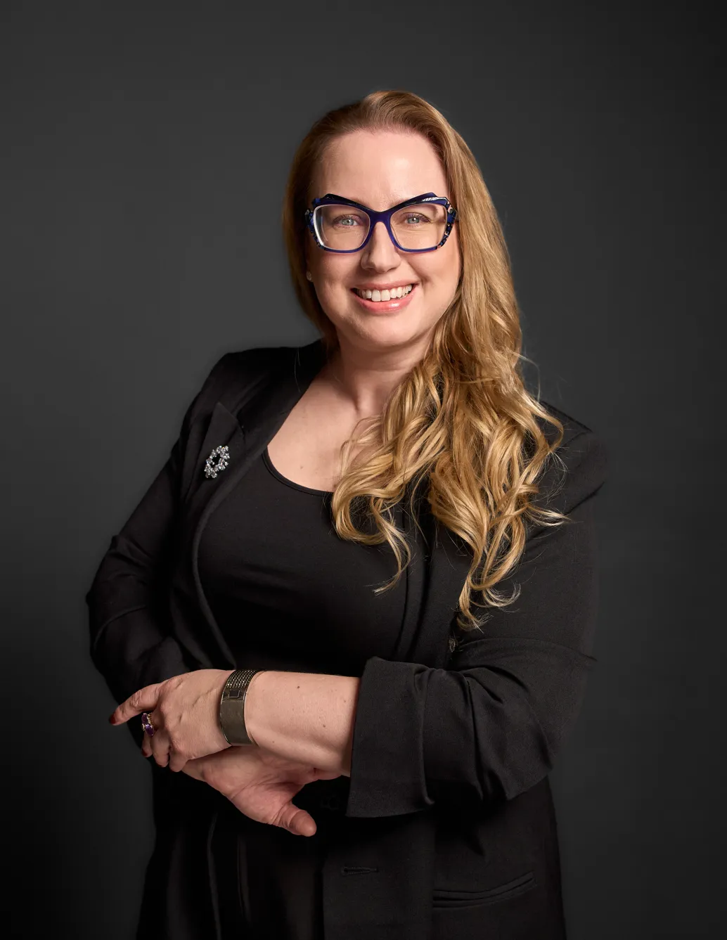 Lawyer in professional attire smiling with arms crossed against a neutral background.