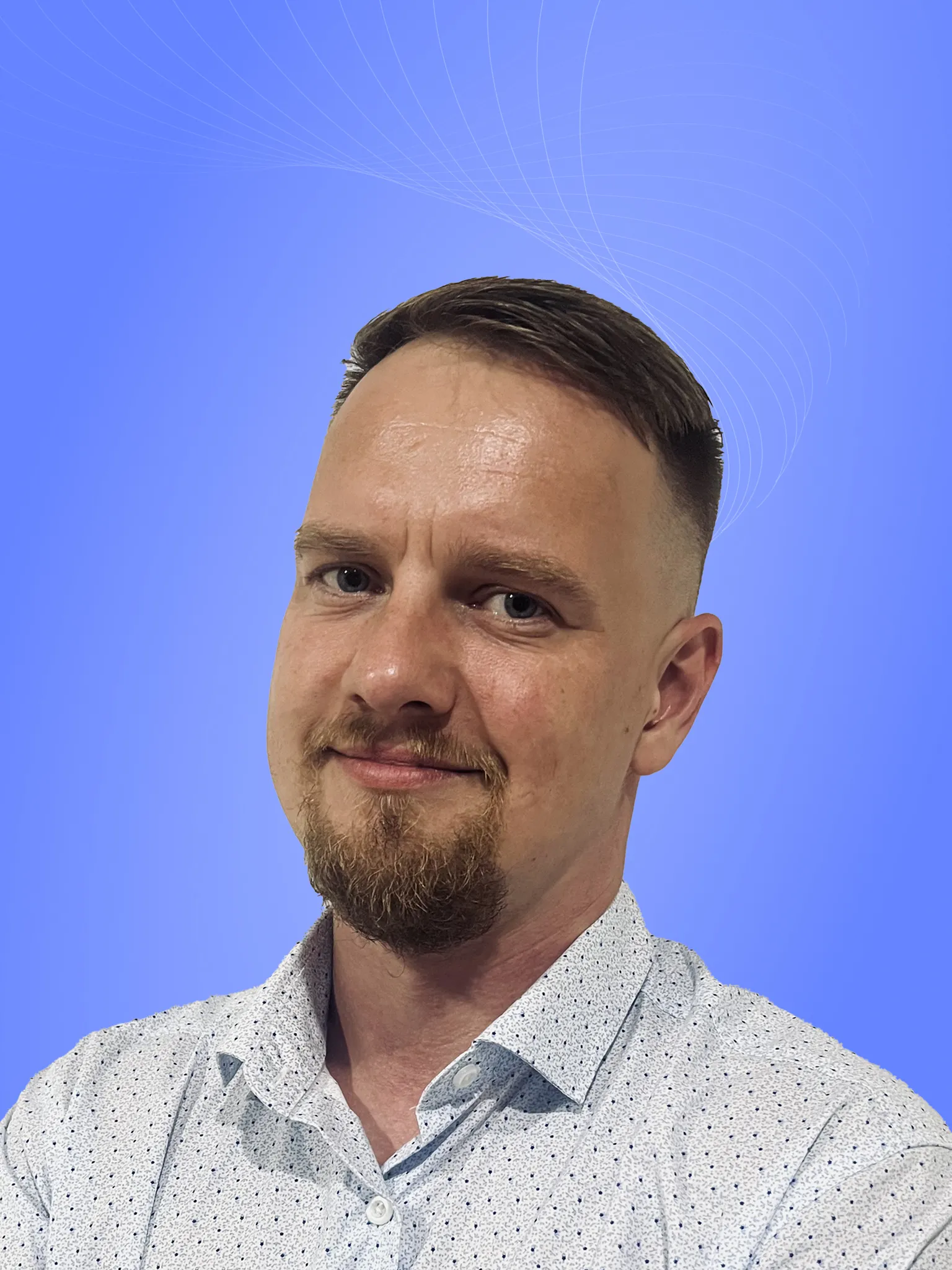 Professional with short hair and beard, wearing a polka-dotted shirt, smiling against a blue background.