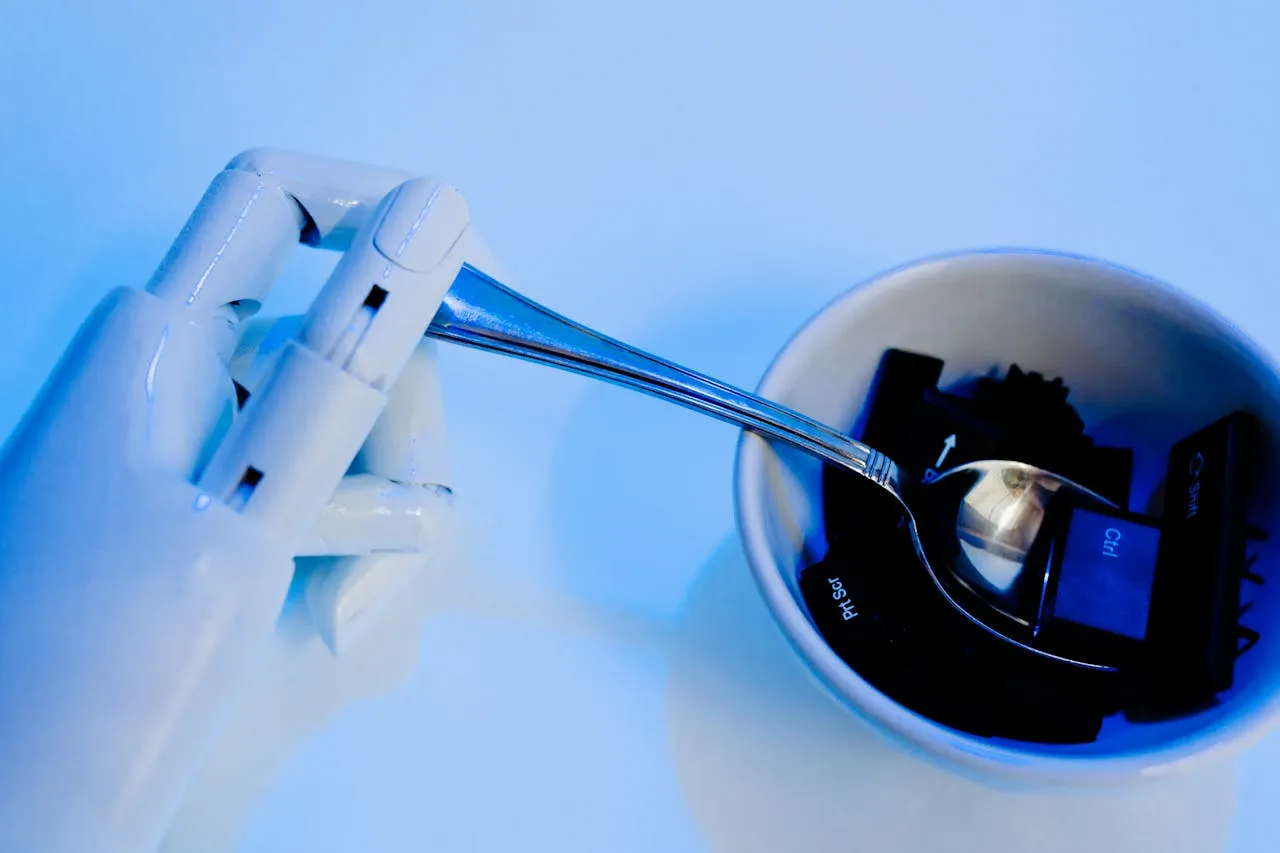 Robot hand holding a spoon, positioned over a bowl containing black keyboard keys.
