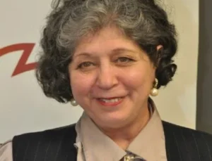 Legal professional with short curly hair, wearing a pinstriped suit and smiling at a formal event.