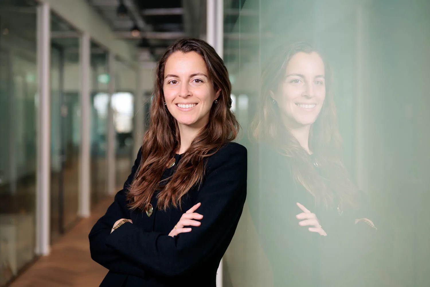 Legal professional smiling with arms crossed in a modern office setting.