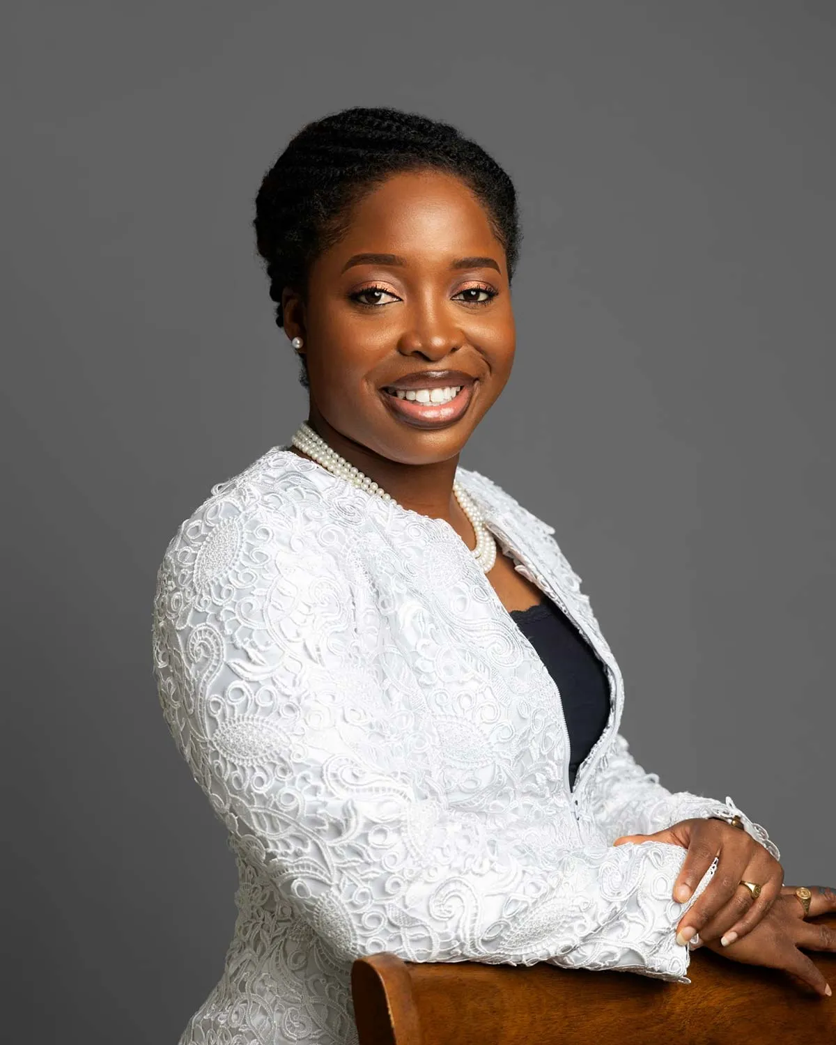 Attorney smiling confidently with arms crossed, wearing a white jacket in a professional portrait setting.