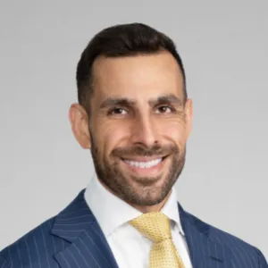 Lawyer smiling confidently, dressed in a suit and tie, against a neutral background.