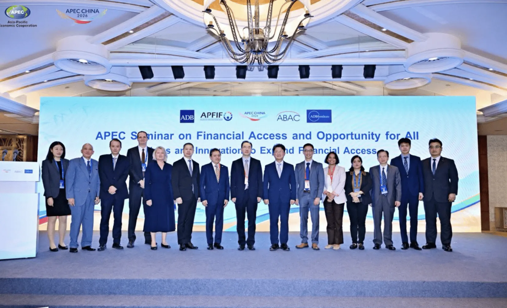 Group of professionals posing at APEC seminar on financial access and opportunity with banners in the background.