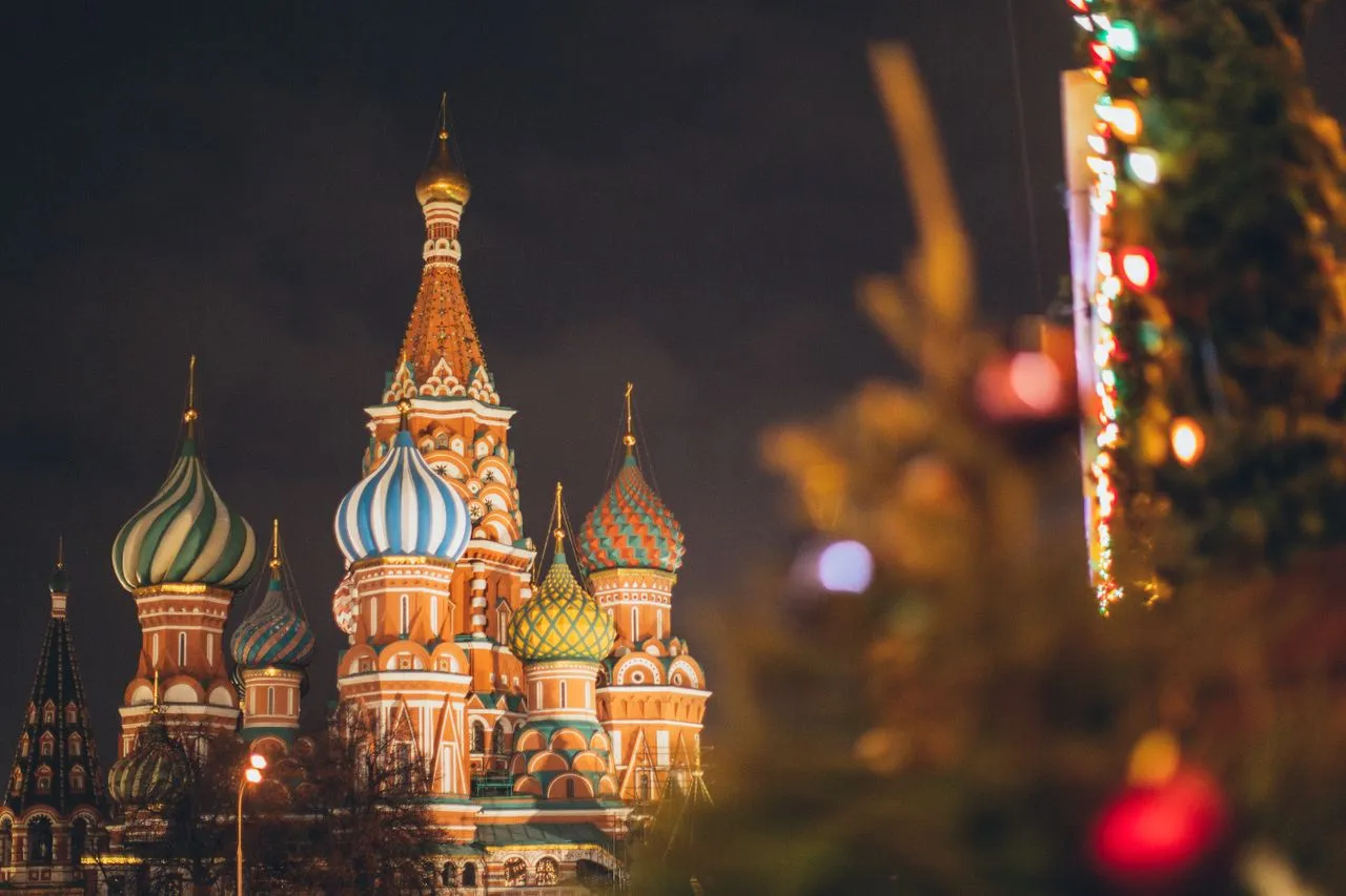 Colorful domes of St. Basil's Cathedral illuminated at night with holiday decorations in the foreground.