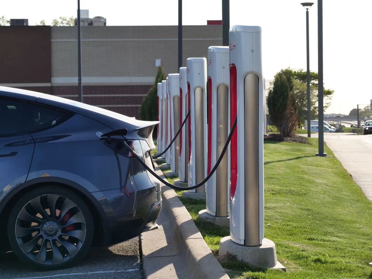 Electric vehicle charging station with a gray car connected to a charging cable.