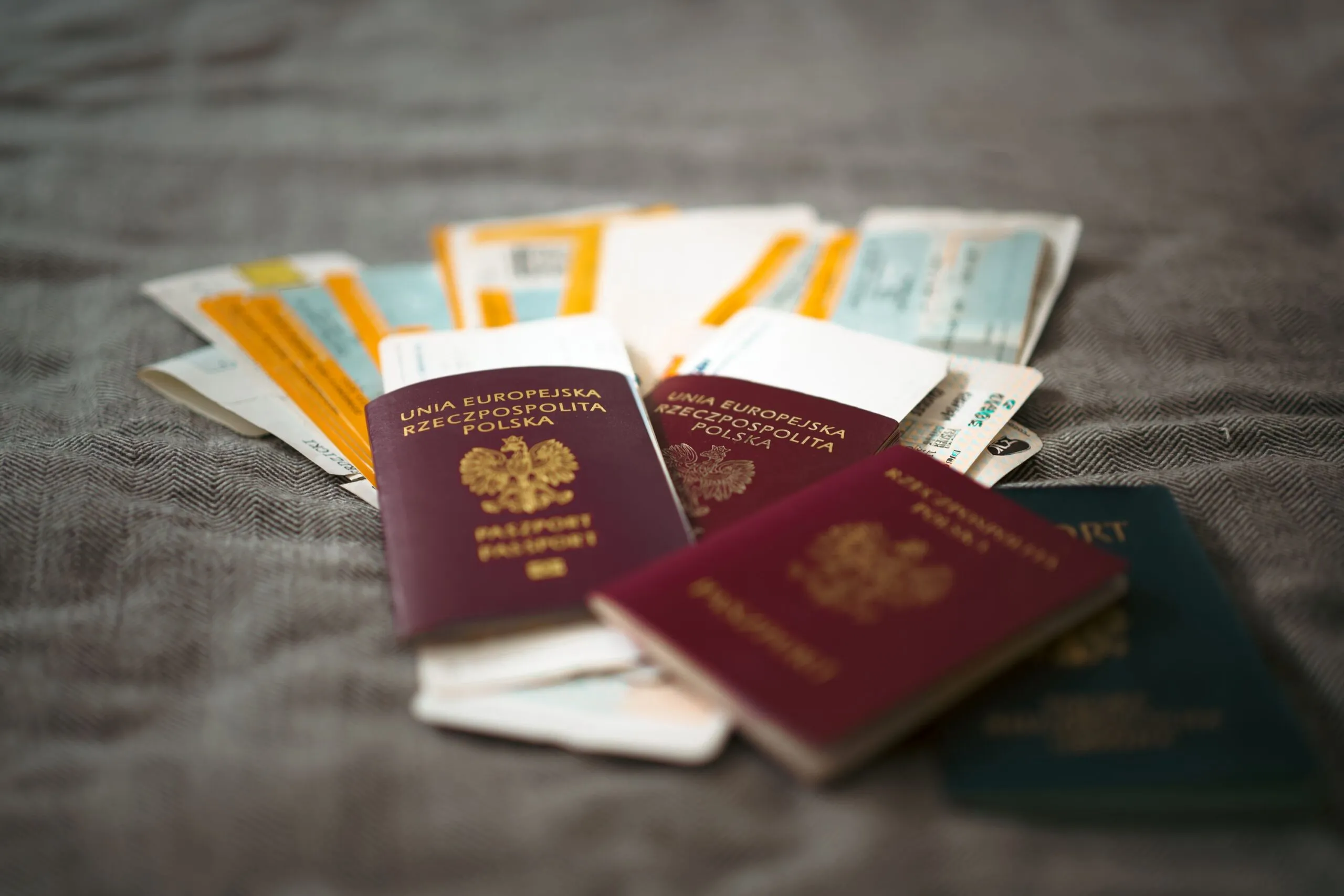 Multiple passports and travel documents arranged on a textured surface.
