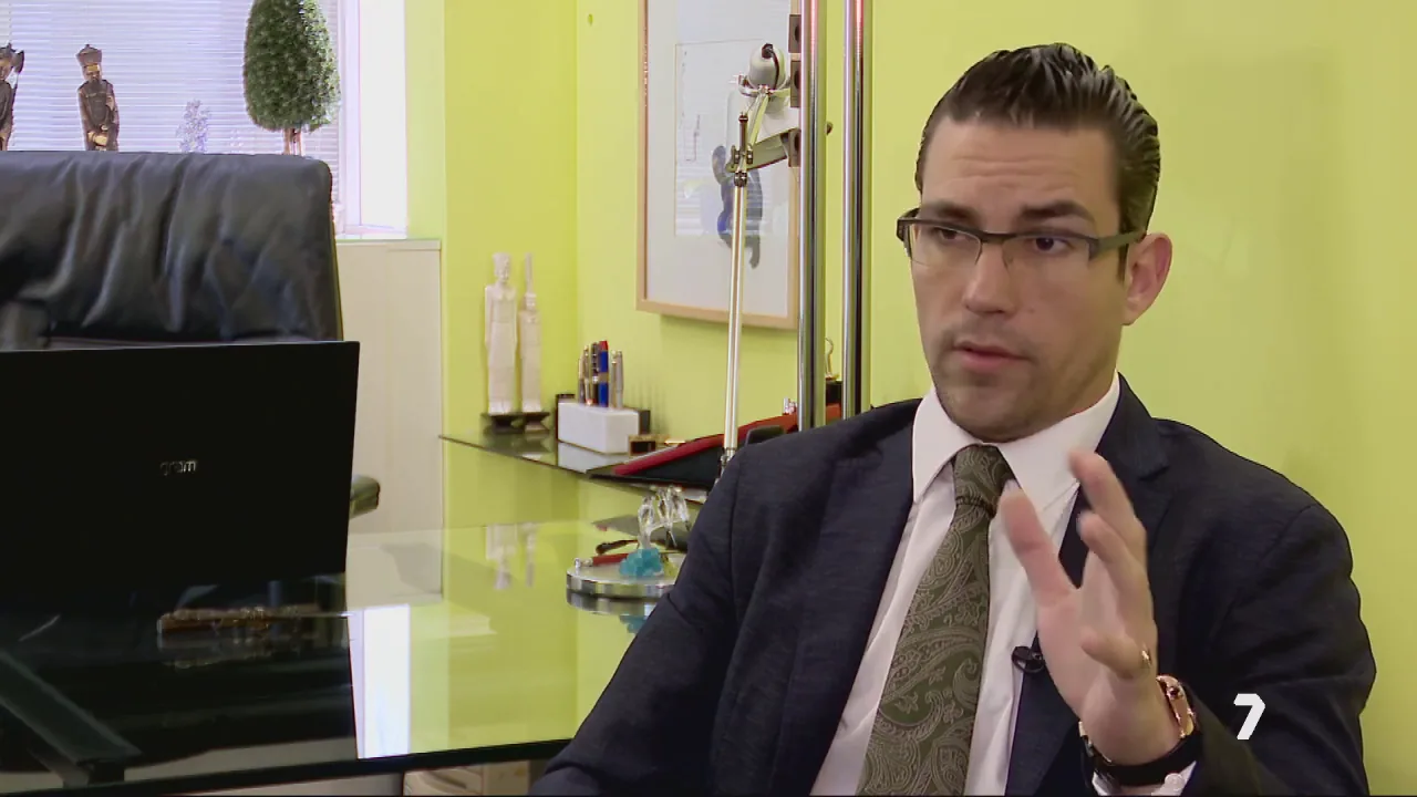 Attorney discussing legal matters while seated at a desk in a brightly colored office.