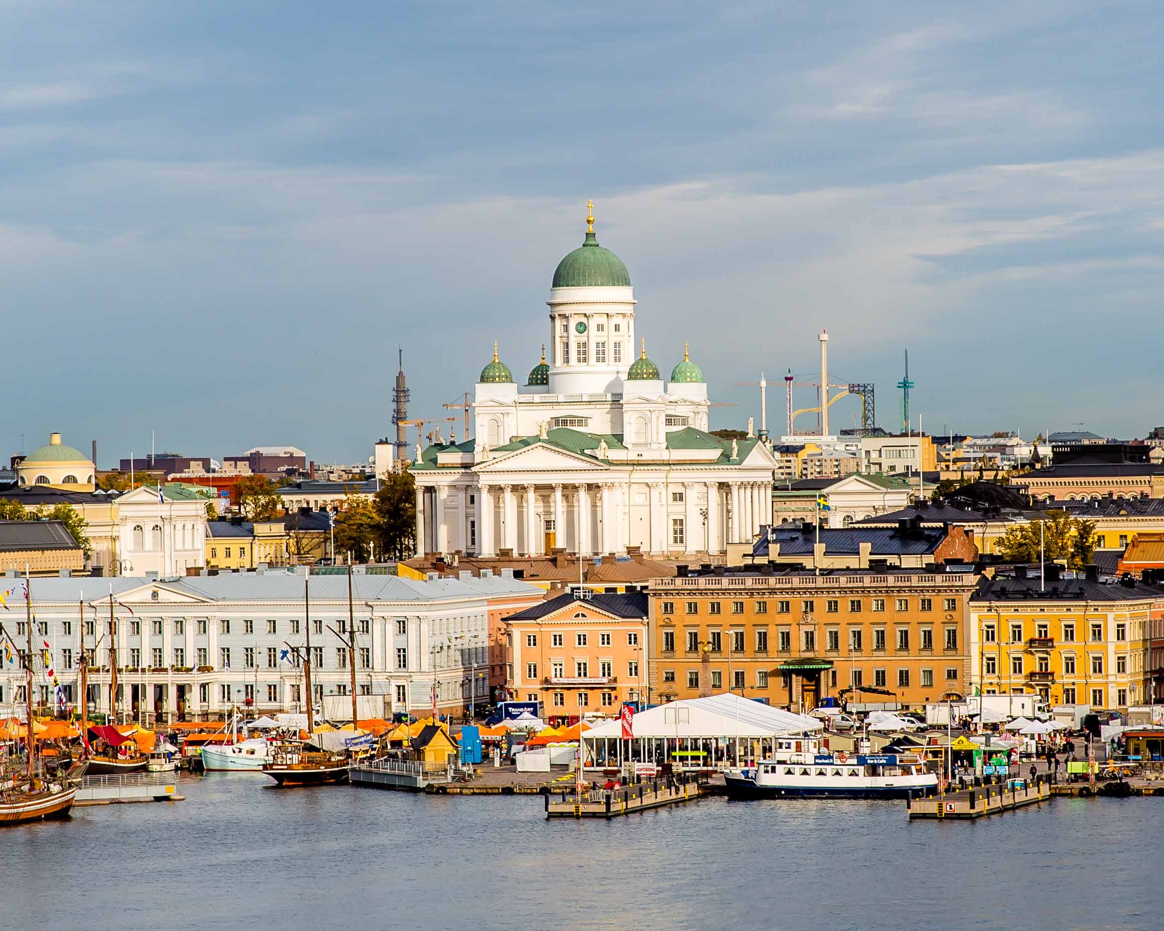 Cityscape view of Helsinki with historic buildings, waterfront market, and boats along the harbor.