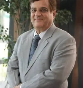 Lawyer in a light gray suit standing confidently, with greenery and modern decor in the background.