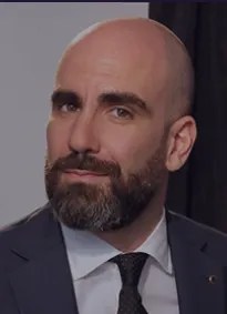 Lawyer posing confidently, wearing a suit and tie, against a neutral background.