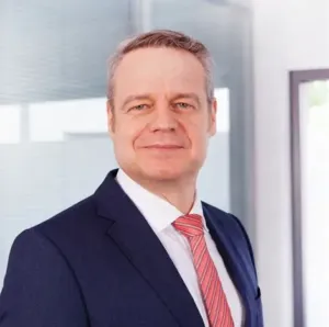 Professional man in a suit standing confidently in a modern office environment.