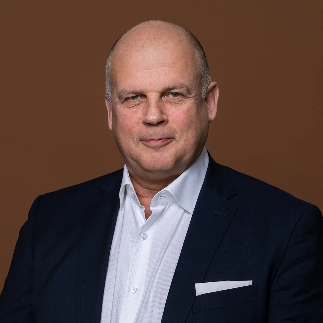 Lawyer portrait against a brown background, wearing a dark suit and white shirt, displaying a confident expression.