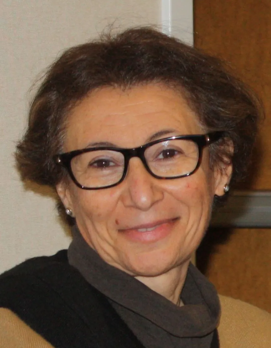 Legal professional smiling, wearing glasses, in a neutral setting, possibly a law office or conference room.