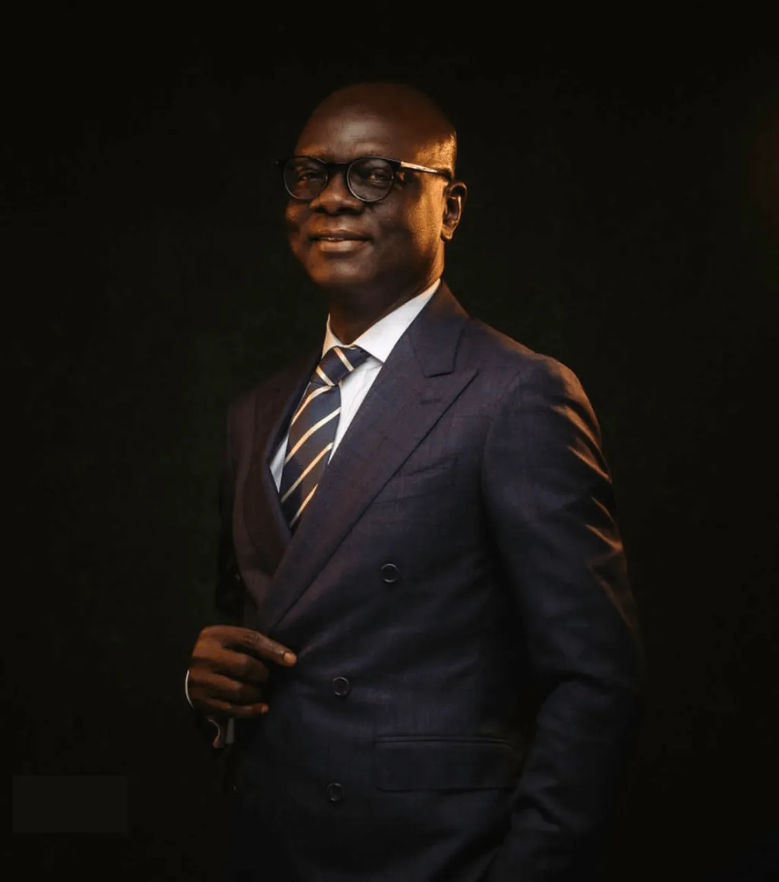 Attorney dressed in a dark suit and glasses, posing confidently against a dark background.