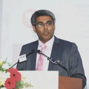Attorney speaking at podium, presenting in a professional setting with floral arrangement in the foreground.