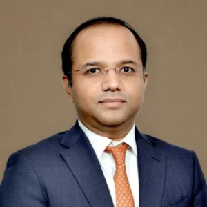 Attorney in a formal suit against a neutral background, presenting a professional demeanor.