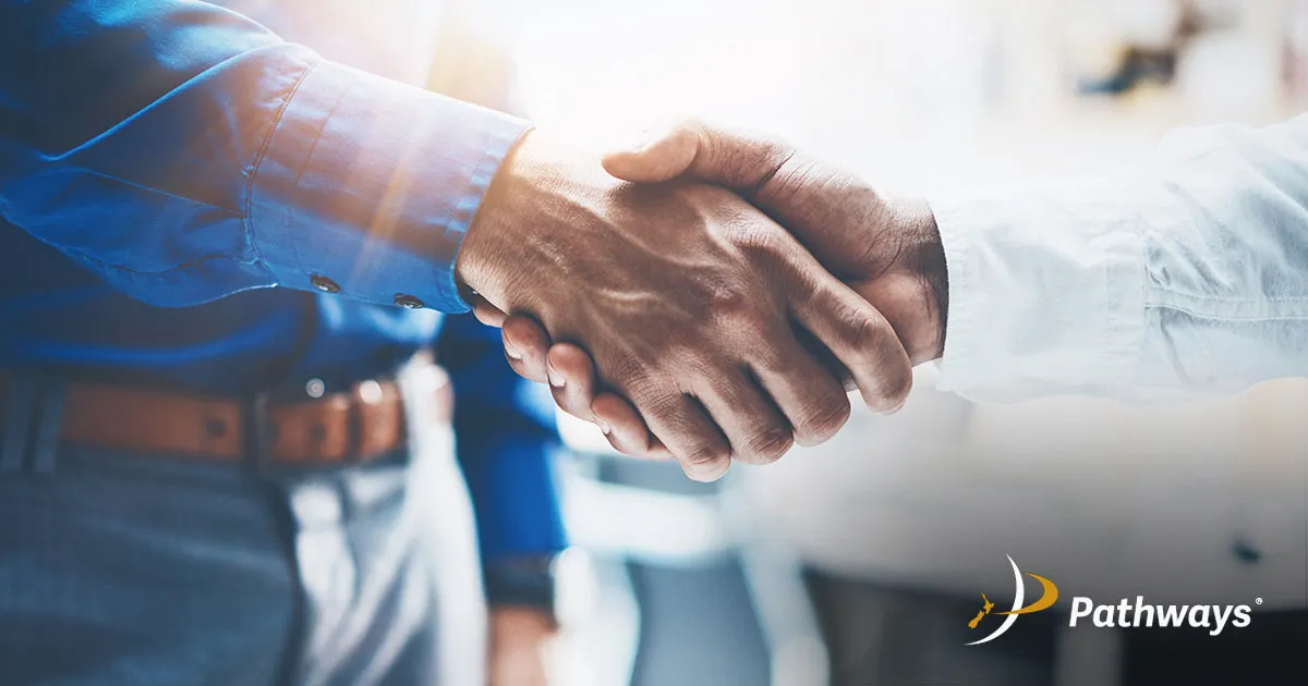 Two individuals shaking hands in a professional setting, symbolizing agreement or partnership.