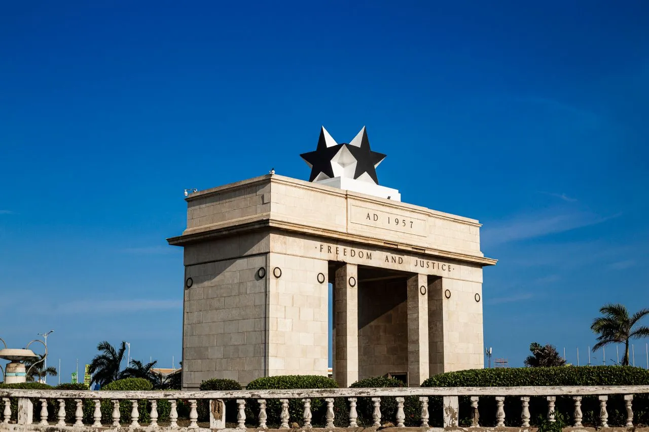Monument featuring large stars above the inscription "Freedom and Justice," set against a clear blue sky.
