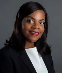 Attorney smiling, wearing a blazer, posing against a neutral background.