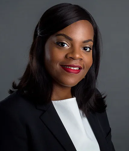 Attorney smiling, wearing a blazer, posing against a neutral background.
