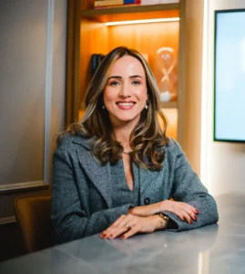 Lawyer smiling at desk in modern office, hands resting on the table.