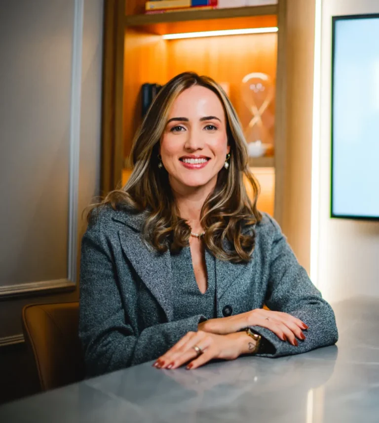 Lawyer smiling at desk in modern office, hands resting on the table.