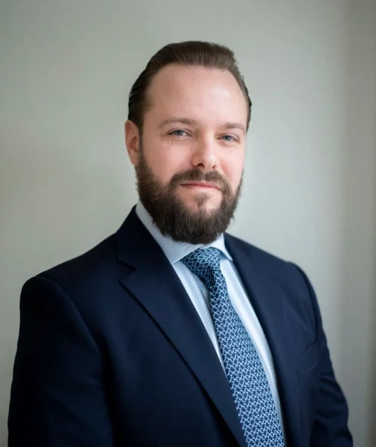 Attorney posing confidently in professional attire with a neutral background.