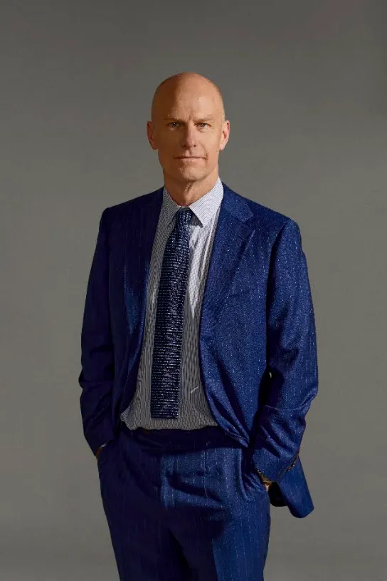 Lawyer in a blue suit standing confidently against a neutral background.